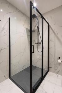 a shower in a bathroom with white marble walls at Ocean Breeze Apt 3 in Dunfanaghy +62 photos