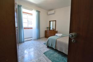 a bedroom with a bed and a dresser and a window at Casa Pedra da Paciência in Monsanto