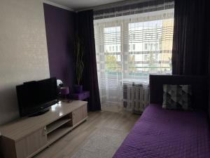 a purple bedroom with a bed and a tv at Elena in Rivne