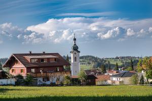 a building with a clock tower in a village at Scheidegg unterm Kreuzberg in Scheidegg