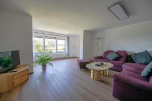 a living room with purple couches and a tv at Scheidegg unterm Kreuzberg in Scheidegg