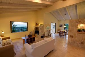 a living room with white furniture and a stone fireplace at Villa Kteni Ideales Resort in Kefallonia