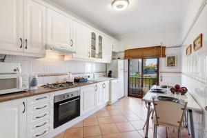 a kitchen with white cabinets and a table and chairs at Cosy Apartment with Pool 1 in Vilamoura