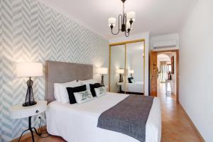 a bedroom with a large white bed and a mirror at Cosy Apartment with Pool 1 in Vilamoura +17 photos