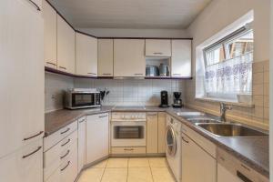 a kitchen with white cabinets and a sink and a microwave at Stricker in Markelfingen