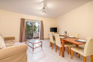 a living room with a dining room table and a couch at Cool Motion Rocha Beach T2 in Portimão
