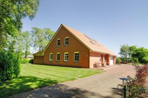 a large brown house with a grass yard at Ferienwohnung Otte in Apen