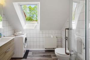 a white bathroom with a toilet and a window at Ferienwohnung Otte in Apen +20 photos