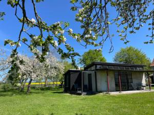 a small black and white building in a field with trees at Ferienwohnung Teehaus in Saal +16 photos