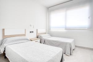 two beds in a white room with a window at Casa Mar y Sol in Los Belones +18 photos