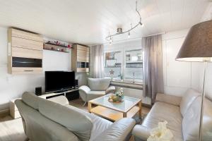 a living room with white couches and a tv at Pension Neuenrade in Neuenrade