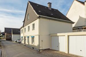 a white building with a black roof on a street at Pension Neuenrade in Neuenrade