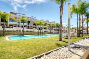 a swimming pool with palm trees and a building at Casa Mar y Sol in Los Belones