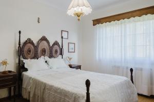 a bedroom with a large bed with white sheets and a chandelier at Quinta do Passal - Gondoriz in Gondoriz