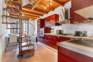 a kitchen with red cabinets and a spiral staircase at Casa vacanze vigna del Lago in Dongo