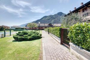 a brick walkway in a yard with a fence and bushes at Casa vacanze vigna del Lago in Dongo