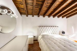 a bedroom with a white bed and a wooden ceiling at L'antica Lugana front lake in Sirmione