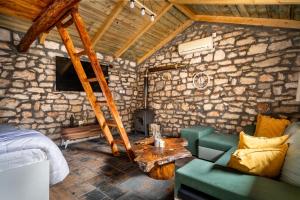 a bedroom with a stone wall with a bed and a couch at Villa Nikos in Kefallonia