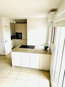 a kitchen with white cabinets and a counter top at Superbe duplex au pied de la plage in Mimizan +3 photos