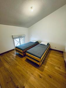 two beds in a room with wooden floors at Superbe duplex au pied de la plage in Mimizan