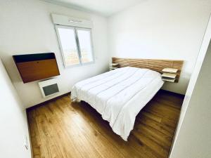 a bedroom with a bed and a flat screen tv at Superbe duplex au pied de la plage in Mimizan
