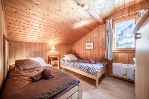 a bedroom with two beds in a wooden room at Chalet Des Charmes in Thollon
