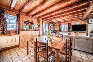 a kitchen and dining room with a wooden table and chairs at Chalet Des Charmes in Thollon