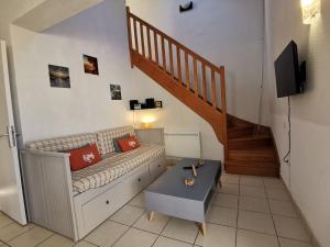 a living room with a couch and a staircase at Maison dans résidence mer - piscine in Loc-Maria-Plouzané