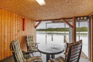 a porch with a table and chairs and a view of the water at Bootshaus Am Müritzarm in Vipperow