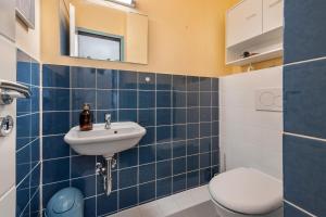 a blue tiled bathroom with a toilet and a sink at Harz Stube in Goslar +15 photos
