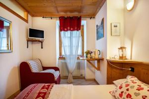 a bedroom with a bed and a chair and a window at Agritur Solasna in Caldes