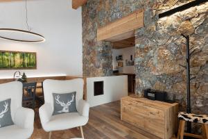 a living room with two chairs and a stone wall at Luxury Chalet Giulia in Torcegno
