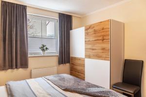 a bedroom with a bed and a chair next to a window at Apart Bergtraum Ried - Typ 1 in Ried im Oberinntal