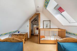 a attic room with two beds and a crib at Bi uns to hus - Morgensünn in Nordstrand