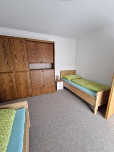 a bedroom with two beds and wooden cabinets at Haus Rose in Kaisersberg