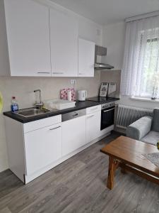 a kitchen with white cabinets and a sink and a table at Haus Rose in Kaisersberg