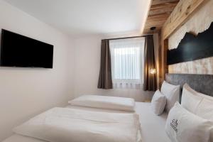 a bedroom with two beds and a flat screen tv at Chalet-Suite Wiese in Selva dei Molini