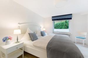 a white bedroom with a large bed and a window at Ferienwohnung Angeln in Ulstrupfeld