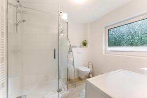 a white bathroom with a shower and a toilet at Ferienwohnung Angeln in Ulstrupfeld