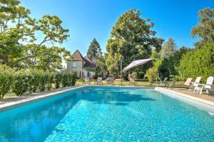 a swimming pool with chairs and a house in the background at Magnifique maison à Ribérac in Ribérac