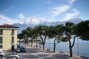 a street with cars parked next to the water and mountains at Lake view Domaso in Domaso