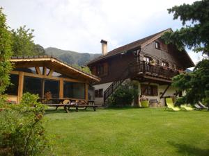 a house with people sitting on a picnic table in the yard at Chambres d'hôtes le génépi in Valdeblore