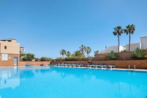 a large swimming pool with chairs and palm trees at Apartamento Relax and Dream in Pájara
