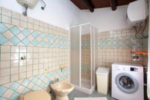 a bathroom with a toilet and a washing machine at Casa Euforbia in Orosei