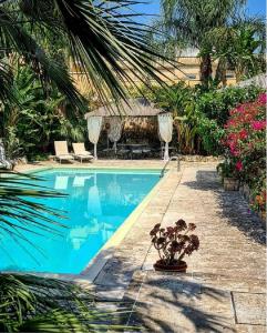 a swimming pool in a yard with trees and flowers at Gli Archi with pool - Lecce in Lecce