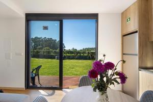a dining room with a table with a vase of purple flowers at Apartamento Thaï com Piscina in Apúlia