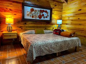 a bedroom with a bed in a room with wooden walls at La Huerta in Mazamitla