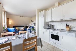 a kitchen with white cabinets and a table with chairs at Bi uns to hus - Morgensünn in Nordstrand
