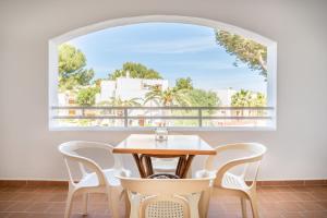 a table and chairs in a room with a large window at Apartamentos Karin 1ºc in Cala d´Or