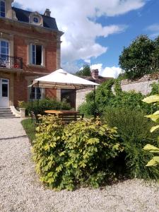a garden with a table and an umbrella in front of a building at BB des 6 arcs"" in Coulonces